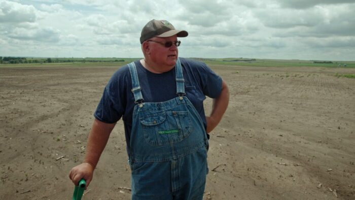 Gabe Brown, a regenerative farmer, stands in a dying field in Common Ground (2023).