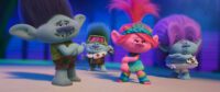 Four trolls practice a song number in Trolls Band Together