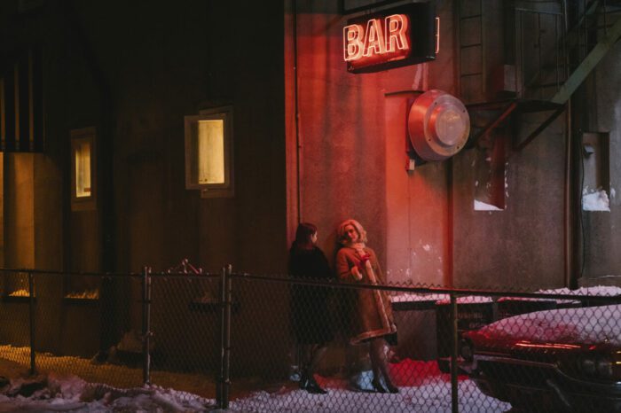 Still from EILEEN showing characters Eileen (left) and Rebecca (right) outside a bar at night. 