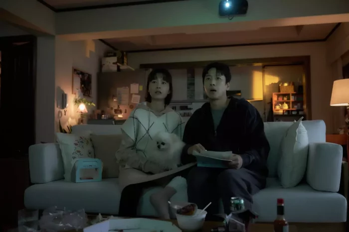 Soo-jin (Jung Yu-mi) and Hyun-su (Lee Sun-kyun) sit on a couch with their dog in Sleep. Photo courtesy of Courtesy Magnet Releasing. 