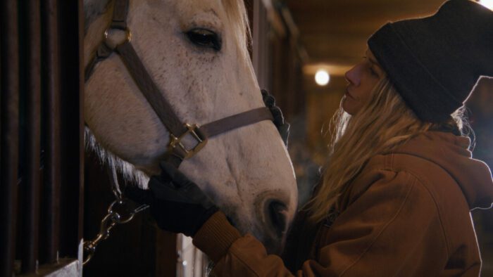 Lindsay Hicks as Jane McSurely taking care of a horse in A Holiday I Do (2023).