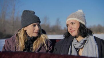 Lindsay Hicks and Rivkah Reyes as Jane and Sue, riding a sleigh through a snowy field in A Holiday I Do (2023).