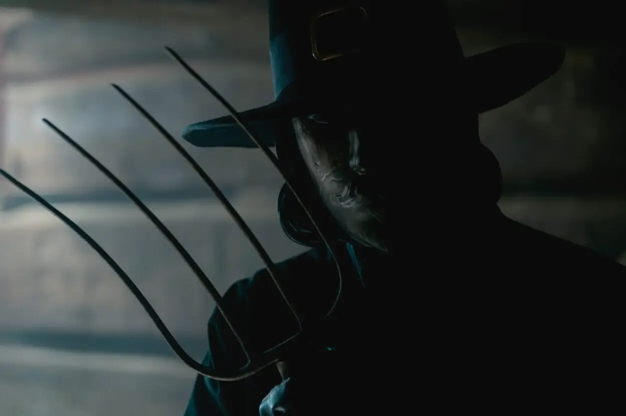 Image from THANKSGIVING featuring a mysterious figure dressed as a pilgrim and wielding a pitchfork.