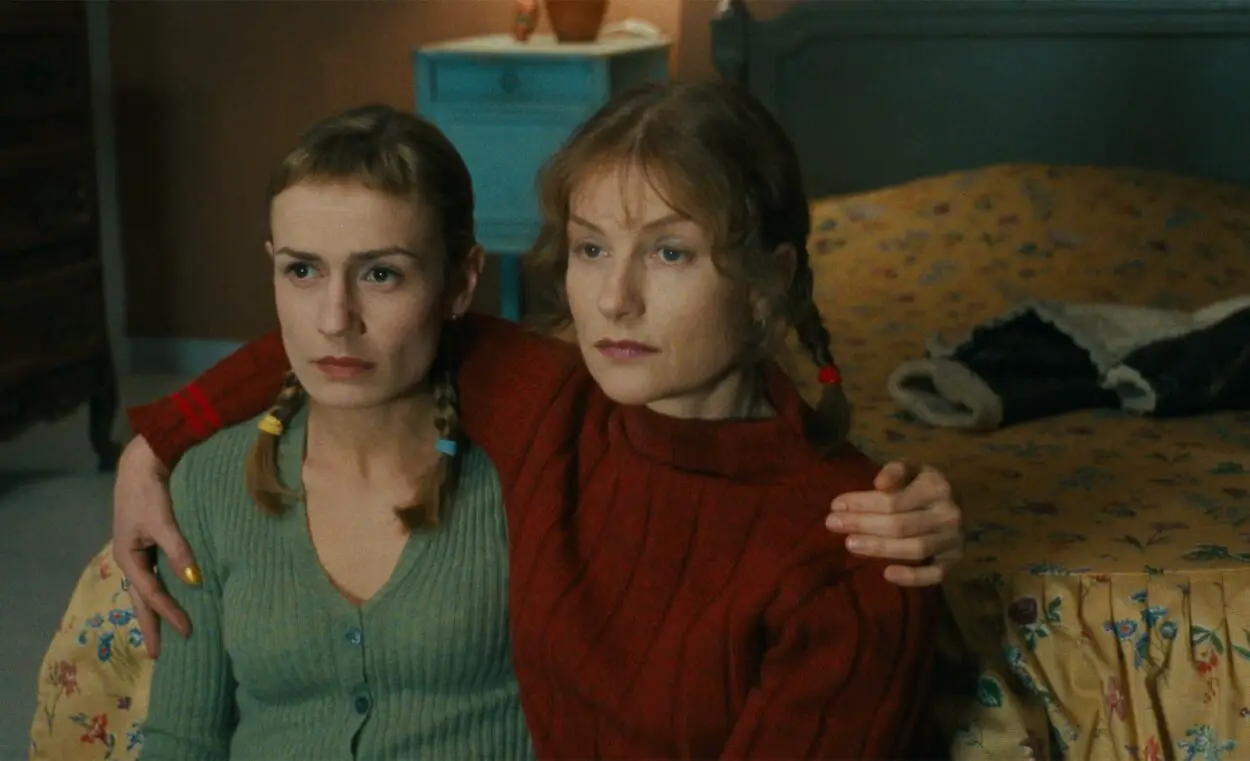 Isabelle Huppert and Sandrine Bonnaire embrace while watching tv in La Ceremonie.