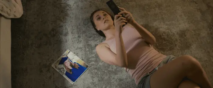 Emily lying on the carpet next to a photo of a girl in a graduation cap and gown