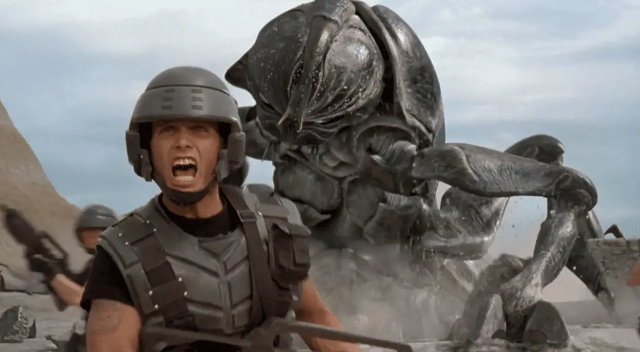 A helmeted soldier turns to warn his battalion about a giant bug in Starship Troopers