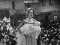 Hester Prynne (Colleen Moore) holds little Pearl (Cora Sue Collins) in her arms as she accepts her punishment in The Scarlet Letter.
