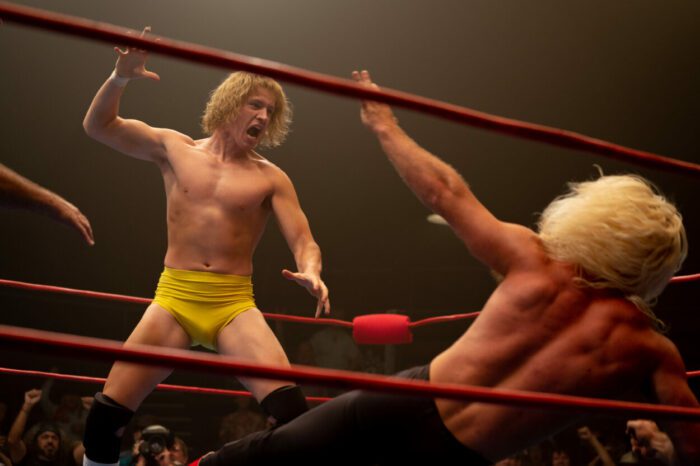 A wrestler with his hand held up threatens anothe wrestler.