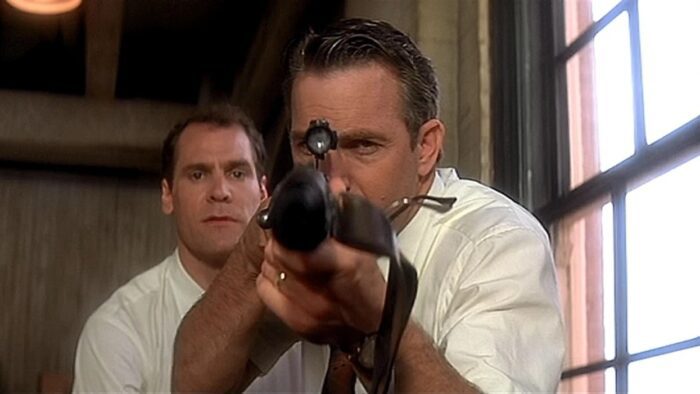 Jim aims a rifle toward the camera with Bill behind him.