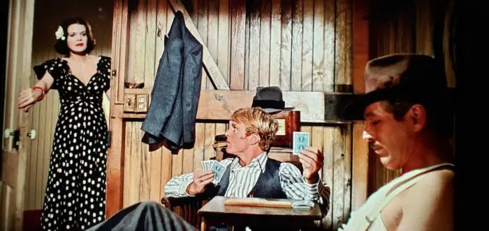[L to R] Eileen Brennan, Robert Redford, and Paul Newman as Billie, Johnny Hooker, and Henry Gondorff in The Sting (1973). Newman and Redford playing cards while Brennan chats with them standing in a doorway. Screen capture off the Universal 100th Anniversary Collectors' Series Blu-ray.