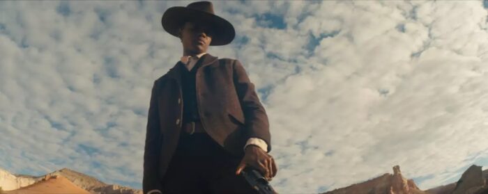 Letitia Wright in <em>Surrounded</em>, wearing a wide brimmed hat and brown suit.