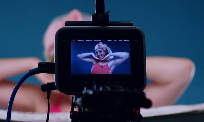Tori is seen in a viewfinder as she poses for a YouTube video.
