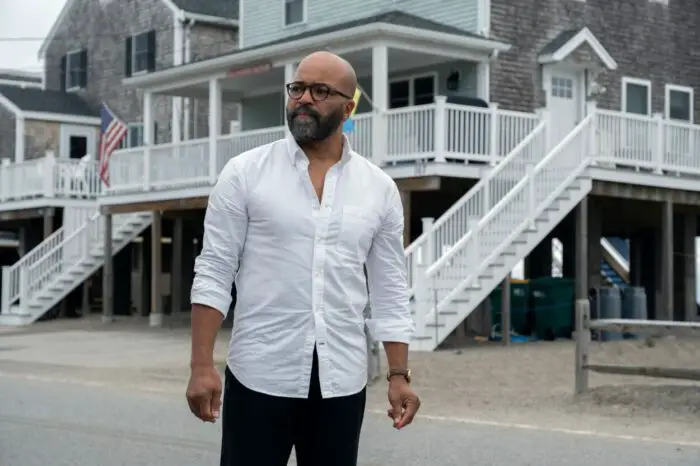 A man in glasses and a white shirts stands on a street of beach homes.