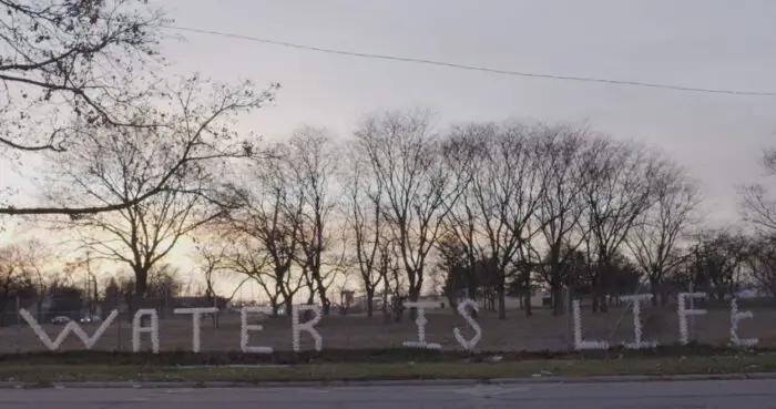 A landscape of Flint, Michigan with the words "Water Is Life" superimposed.