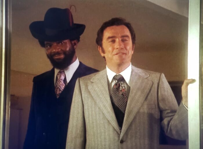 Charles Robinson and Robert Quarry as Fabulous and Morgan in Sugar Hill (1974). Screen capture off Amazon. An American International Picture/MGM. Crime boss Morgan in a suit and time calling on Diana "Sugar" Hill with his henchman Fabulous, a black man in a suit and stylish hat.