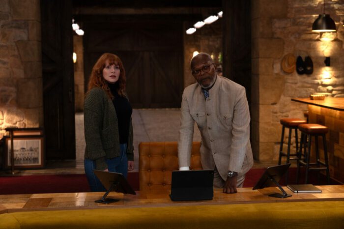 (from left) Elly Conway (Bryce Dallas Howard) and Alfred Solomon (Samuel L. Jackson) in Argylle, directed by Matthew Vaughn. Universal Pictures; Apple Original Films; and MARV. Author Elly Conway and CIA head Alfred Solomon stand at a wooden desk discussing espionage affairs.