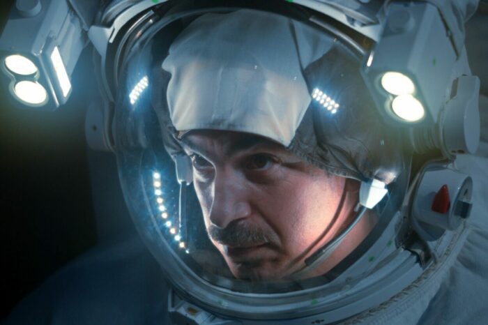 A male astronaut looks out through his helmet.