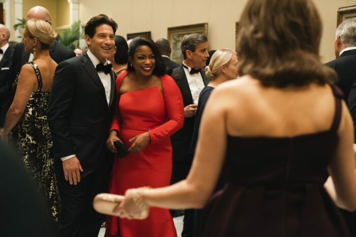 A married couple greets friends at a black tie party.