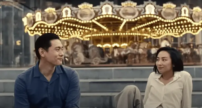 A man and woman sit in front of a carousel