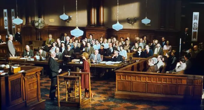 A wide courtroom with lawyers and public attendees is seen in The Verdict.