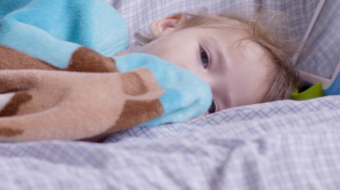 A toddler lays snuggled in bed.