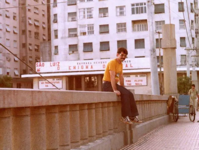 A young man its atop a railing in a city in an historical photo.