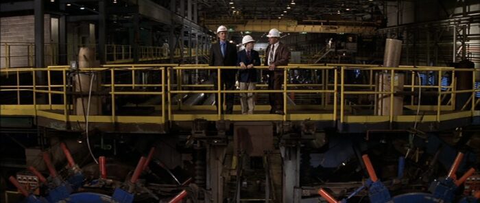 Herman (Bill Murray), Max (Jason Schwartzman) and one of Herman's workers wear hard hats and stand on a factory walkway as they discuss project plans.