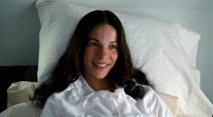 Teresa, in a hospital bed, smiles.