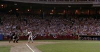 A batter comes up to the plate as the crowd roars behind him.
