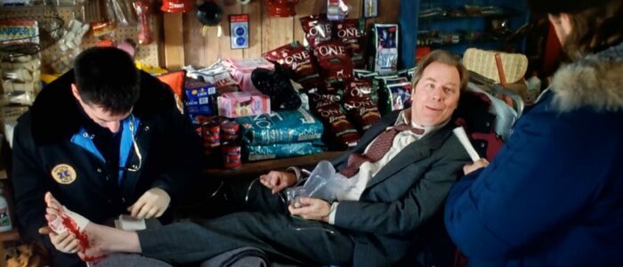 Michael McKean as Mr. Walsh The pristine pond where locals play hockey in Mystery, Alaska (1999). Screen capture off Amazon. Hollywood Pictures/Buena Vista Pictures Distribution. Mr. Walsh, representative of a large big-box store, strapped to a mobile gurney after getting shot in the foot by an irate local.