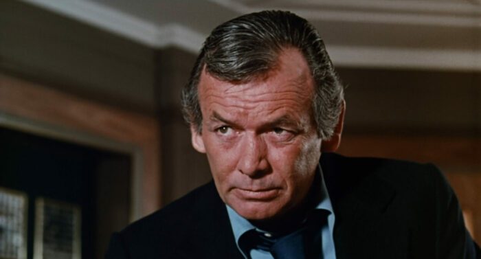 David Janssen, wearing a coat and tie with shirt unbuttoned.