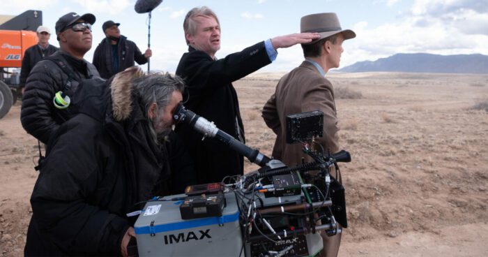 Christopher Nolan (center) directs on the set of Oppenheimer with Cillian Murphy as J. Robert Oppenheimer looking in the distance.