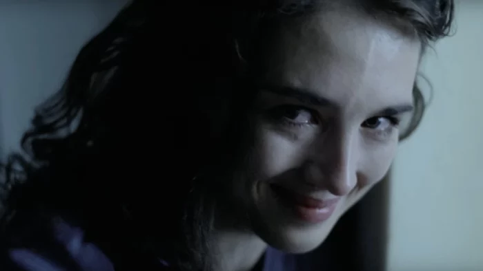 Anna (Isabelle Adjani) in Possession, looking to the camera as she begins crying with a grin on her face.