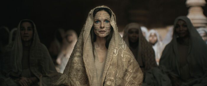 REBECCA FERGUSON as Lady Jessica in Warner Bros. Pictures and Legendary Pictures’ action adventure “DUNE: PART TWO,” a Warner Bros. Pictures release. (PRESS KIT). © 2024 Warner Bros. Entertainment Inc. All Rights Reserved. Photo Credit: Courtesy of Warner Bros. Pictures. A woman with her face tatooed, wearing religious robes, she is the leader of a faith yet their manipulator as well.
