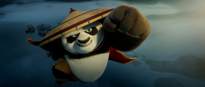 A panda with a hat and cape soars through the sky
