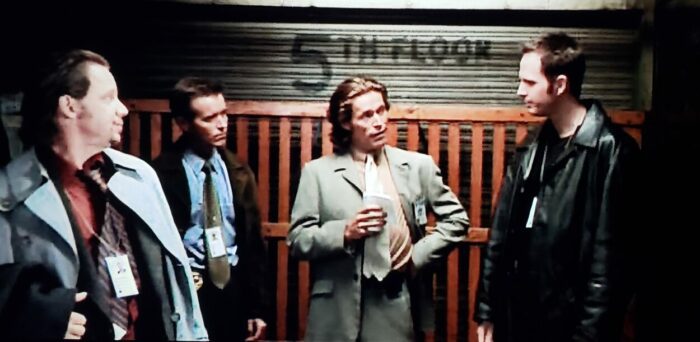[L to R] David Ferry, Brian Mahoney, Willem Dafoe, and Bob Marley as Dolly, Duffy, Smecker, and Greenly in The Boondock Saints (1999). Screen capture off of DVD. Franchise Pictures. Three detectives and FBI Agent Smecker ride a cargo elevator while discussing a crime scene.