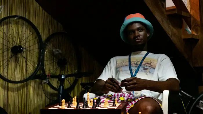 Myles Evans as Townes in Paradise (2023). Young African American man sitting at a chessboard waiting for the game to continue.