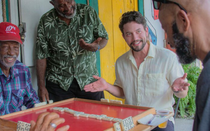 David (Jackson Rathbone) plays dominoes with locals in Books & Drinks.