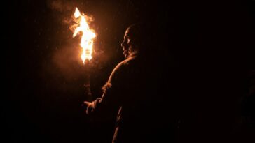 Chuku Modu as Adem in Bleecker Street's OUT OF DARKNESS. Credit: Bleecker Street. Stone age man in furs wanders in the darkest night carrying a torch that barely breaks the darkness.