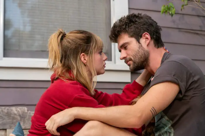 A woman and her boyfriend talk closely on a porch.