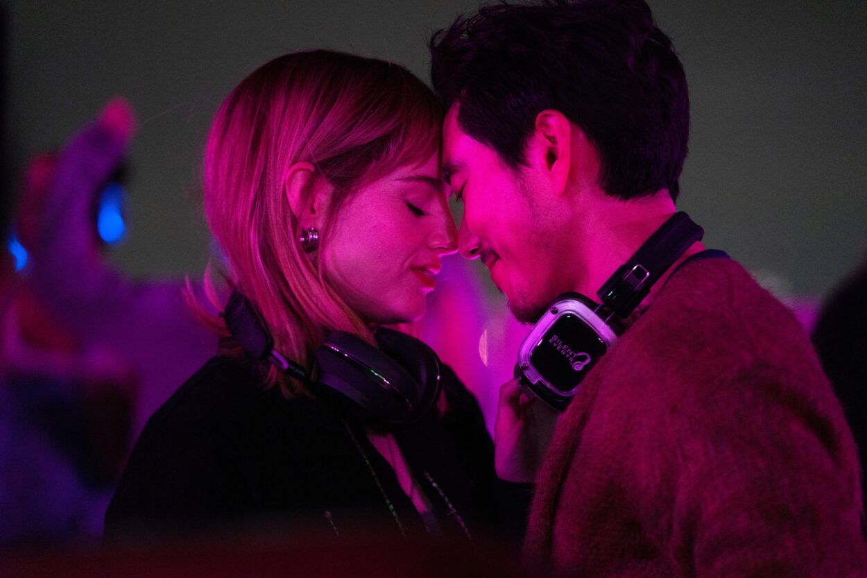 A man and woman wearing headphones dance closely on a rooftop in The Greatest Hits