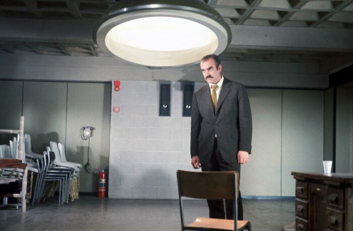 Johnson stands in a room with a chair in front and a light above him in Directed by Sidney Lumet Vol. 1
