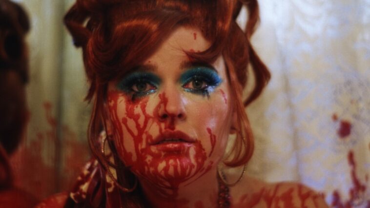Scarlet Moreno as Velma in the short film Velma (2022). Velma's face covered in blood and sporting prominent blue eyeshadow.