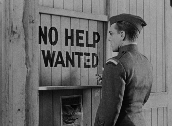 Eddie Bartlett (James Cagney), wearing his service uniform, stares at a "No Help Wanted" sign in The Roaring Twenties.