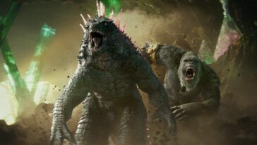 Godzilla with pink spikes yells on the run with a yelling Kong behind them as they head to battle with smoke around them.
