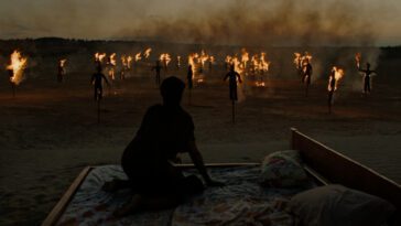 A woman wakes from her bed to find herself on a desert plain, surrounded by burning effigies