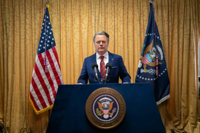 The President of the United States addresses the nation at a podium flanked by flags.