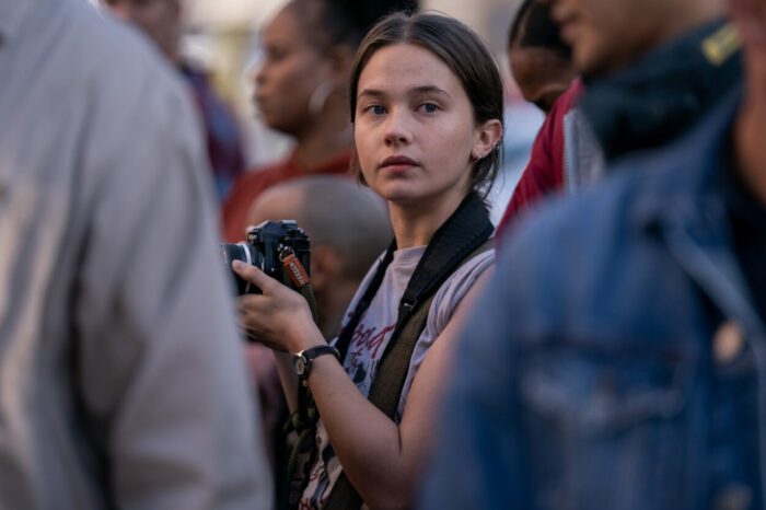 A young photojournalist is seen in a crowd.