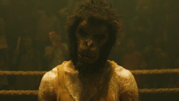 Dev Patel as the Kid in MONKEY MAN, directed by Dev Patel. © Universal Studios. All Rights Reserved. The Kid wears a monkey mask as he stands in a ring waiting for a fight.