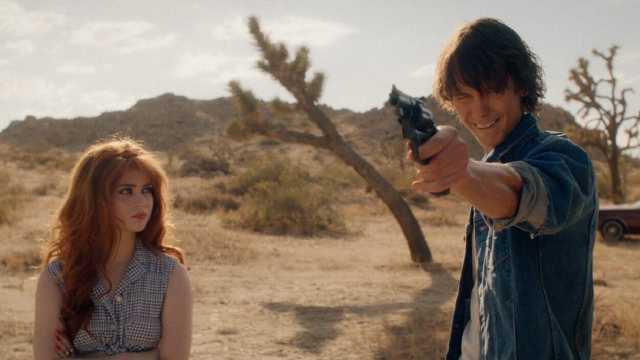 (L-R) Sierra McCormick as Sybil and Ryan Masson as Miles in the western/crime/thriller, THE LAST STOP IN YUMA COUNTY, a Well Go USA release. Photo courtesy of Well Go USA. Teenage couple firing a six-shooter in the desert acting like outlaws they've seen in films.